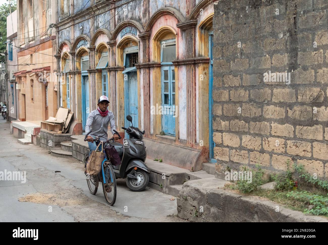 Diu, India - December 2018: A young man riding a bicycle on a street with old Portuguese era houses in the island town of Diu. Stock Photo