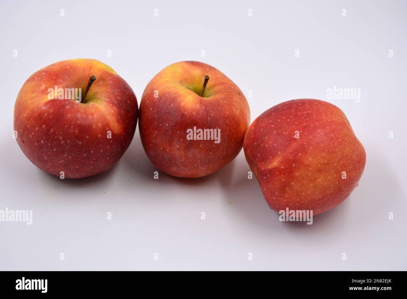 Three large ripe red yellow apples, sweet fruits arranged on a white ...
