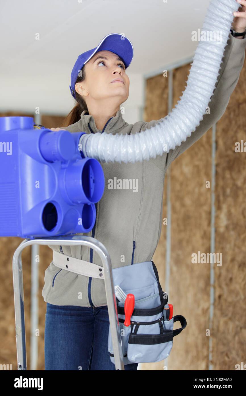 female elctrician fitting air conditions pipes Stock Photo