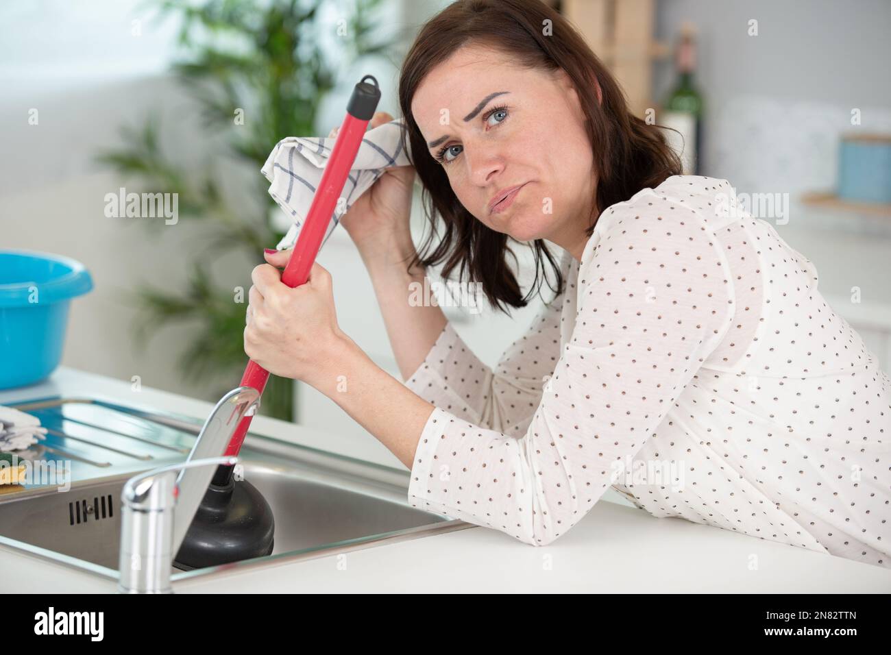 https://c8.alamy.com/comp/2N82TTN/frustrated-woman-using-plunger-in-kitchen-sink-2N82TTN.jpg