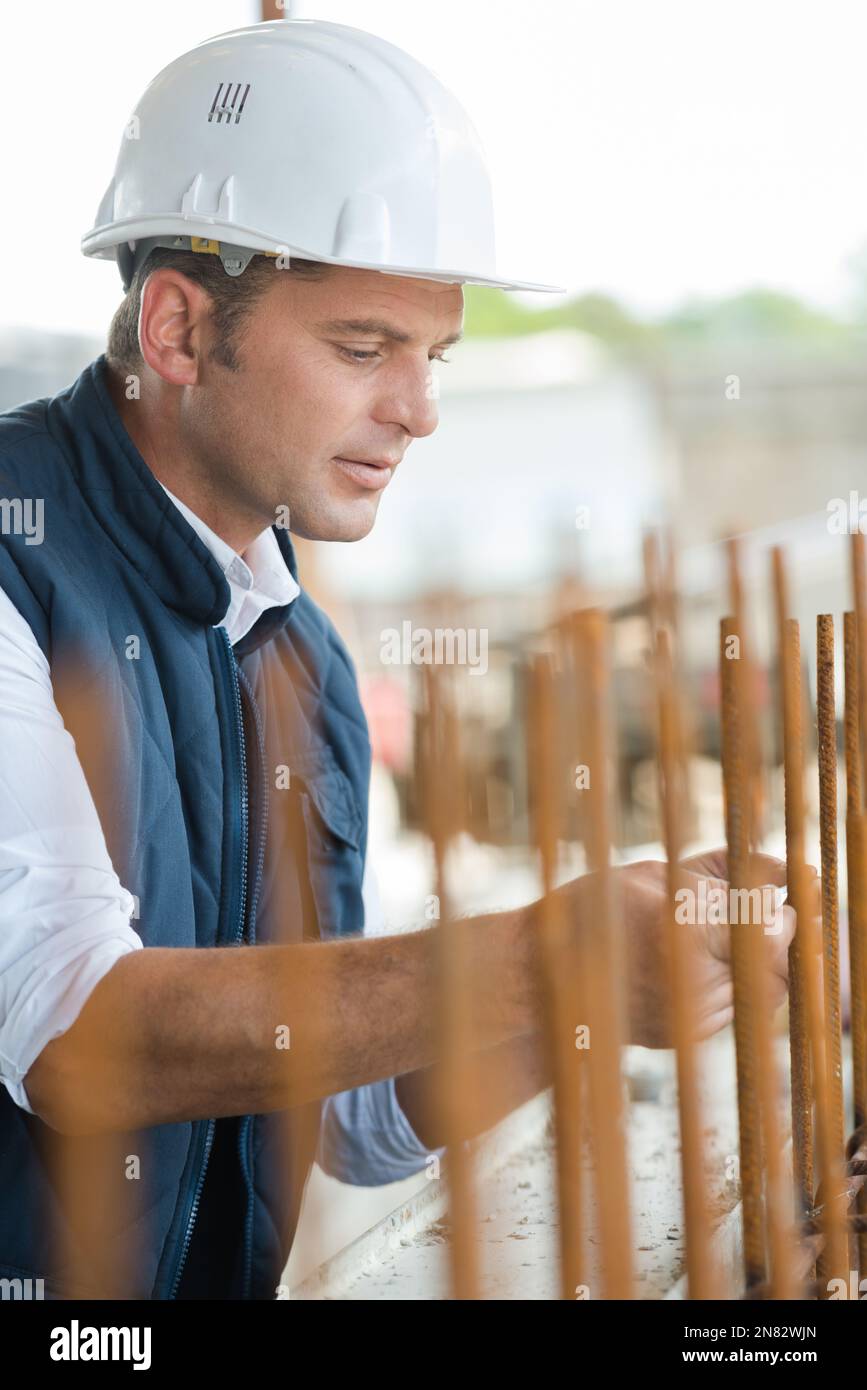 man measuring off metal bar in factory Stock Photo