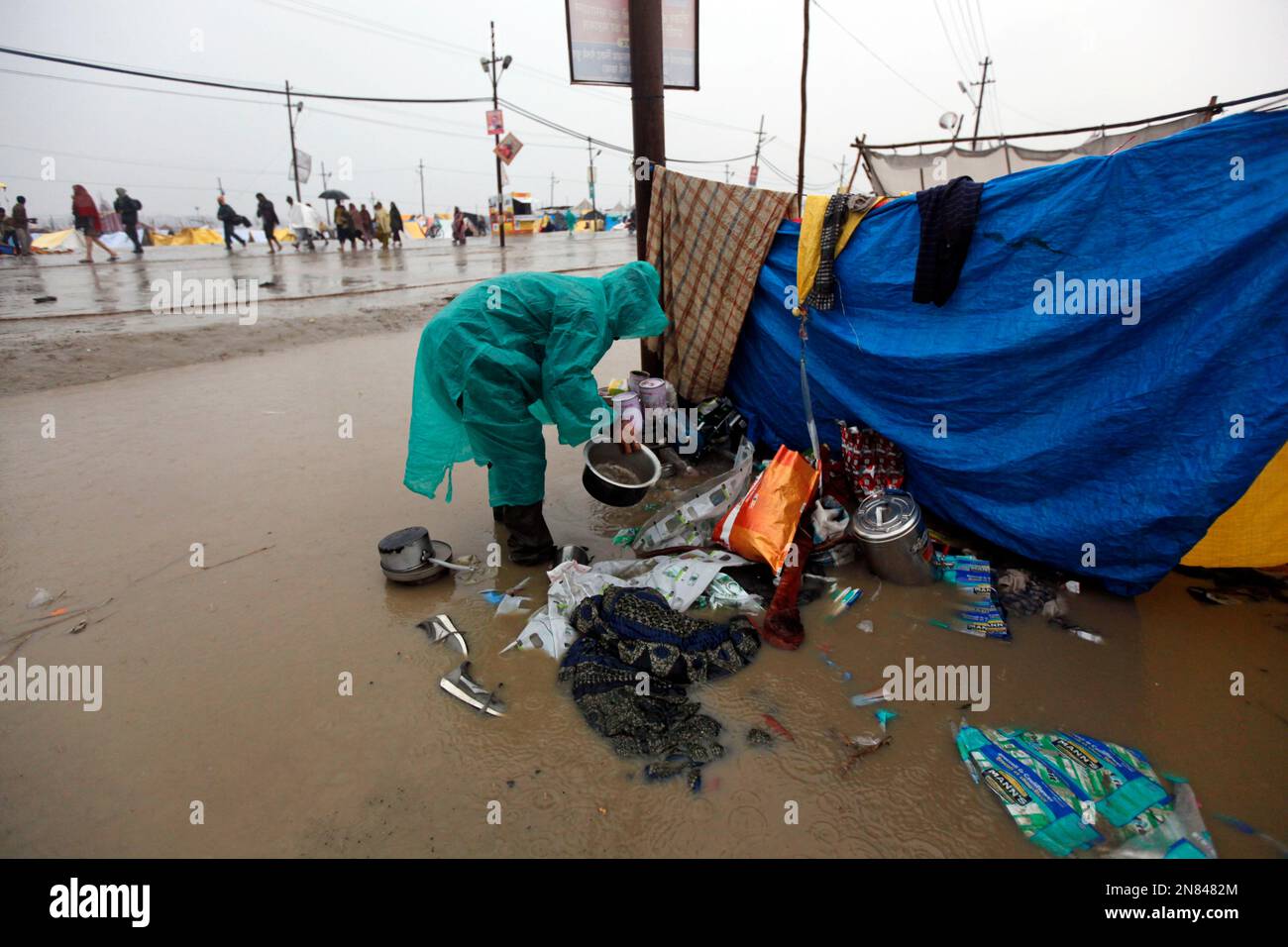 a-hindu-devotee-removing-his-belongings-from-a-flooded-tent-as-it-rains