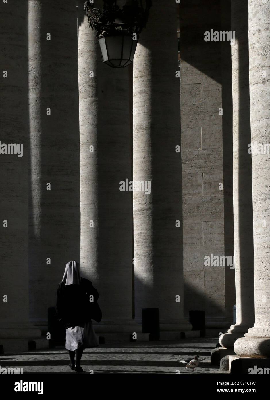 A nun walks under the Bernini colonnade in St. Peter's Square at the