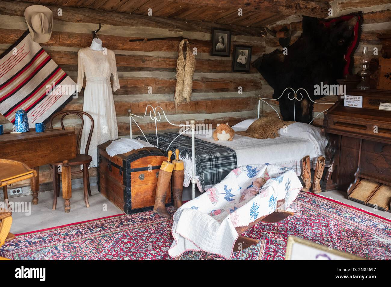 Cody, WY, USA - Jun 25, 2022: Old Trail Town is a tourist attraction with authentic frontier buildings from the late 1800's.  A log cabin bedroom with Stock Photo