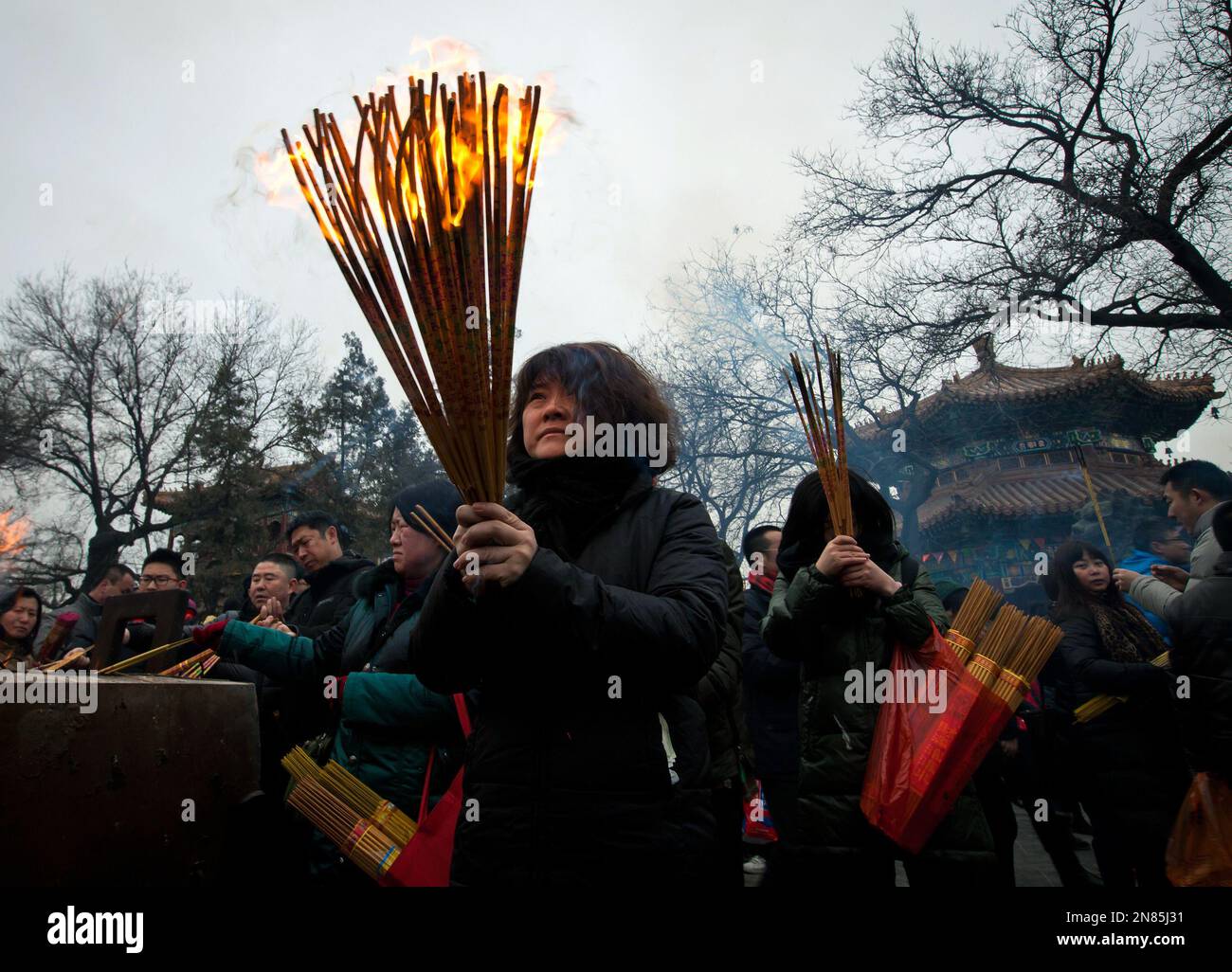 A woman burns incense while praying on the first day of the Lunar New ...