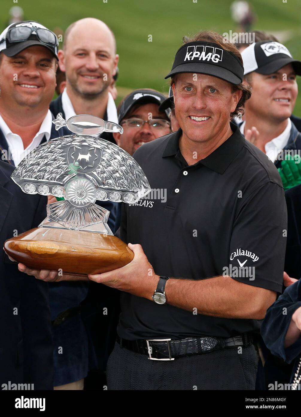 Phil Mickelson holds the championship trophy as he poses for photographers with the Phoenix Thunderbirds after winning the Waste Management Phoenix Open golf tournament on Sunday, Feb