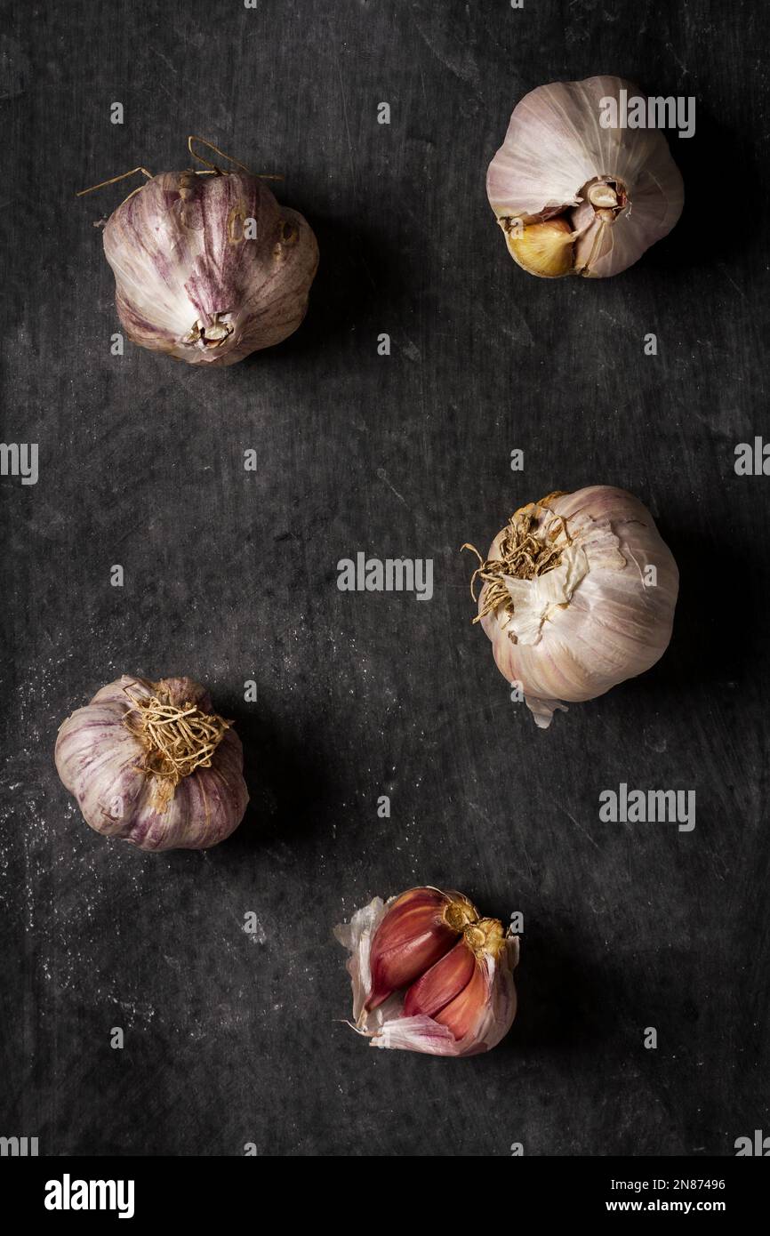 Fresh garlic bulbs and cloves grouped on black background. Flat lay ...