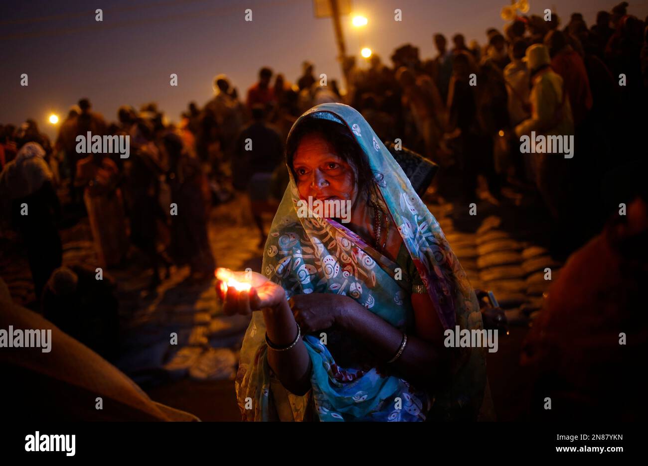A Hindu devotee lights a lamp to worship the river Ganges at "Sangam