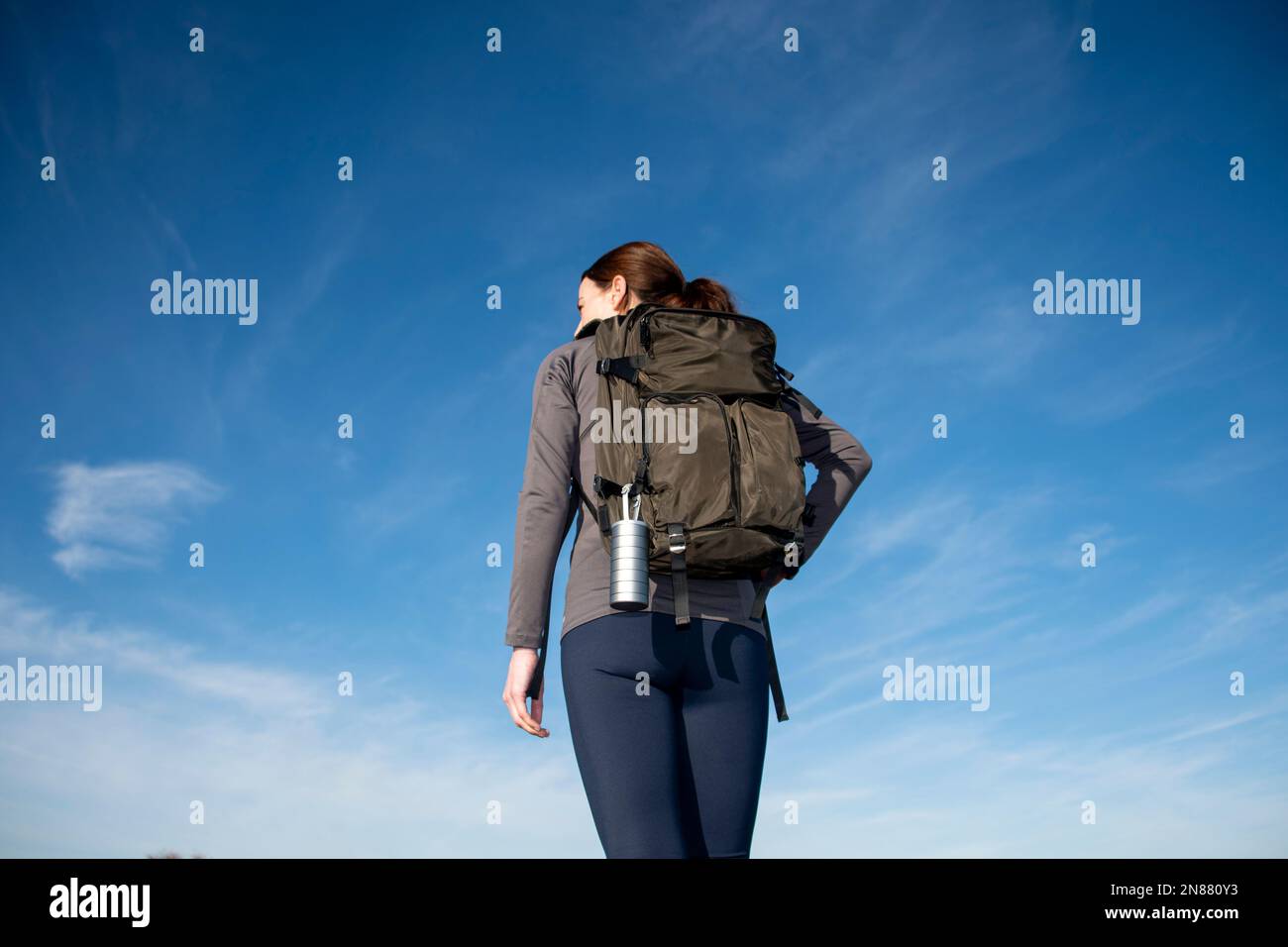 Rear view of a woman backpacker against a blue sky. Stock Photo