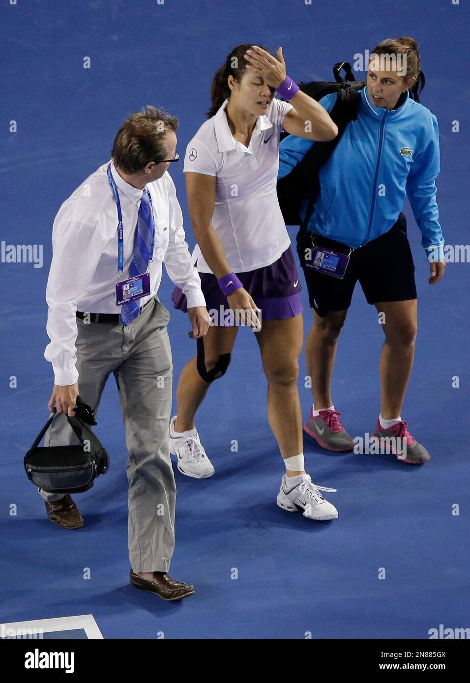 China's Li Na is escorted back to her chair by medical staff after ...
