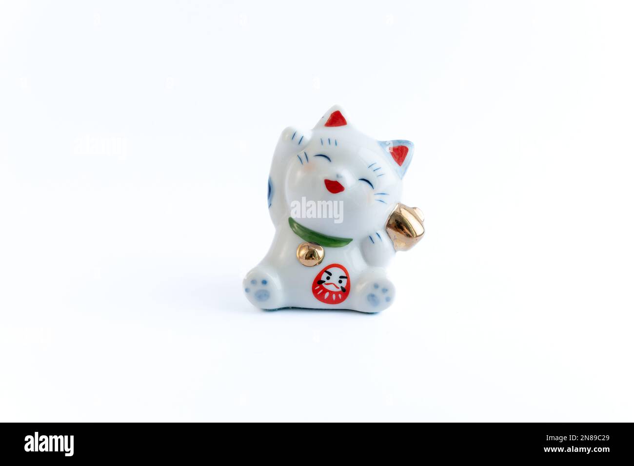 A Maneki-neko or also known as fortune cat in porcelain. Symbolizing luck and wealth, on a white isolated background. Stock Photo