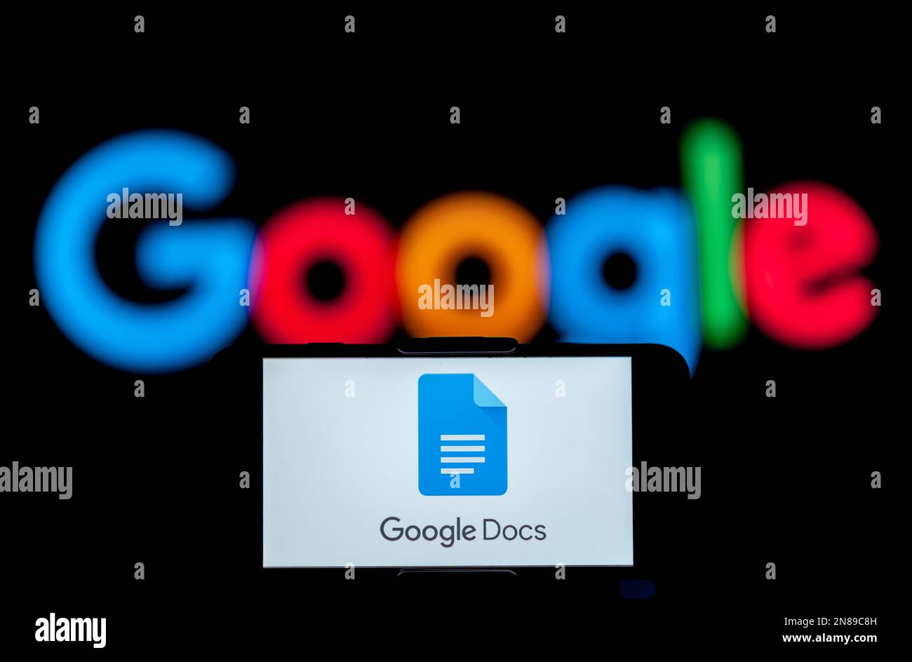In this photo illustration, the logo of a google docs is seen displayed on a mobile phone screen with a google logo in the background. Stock Photo