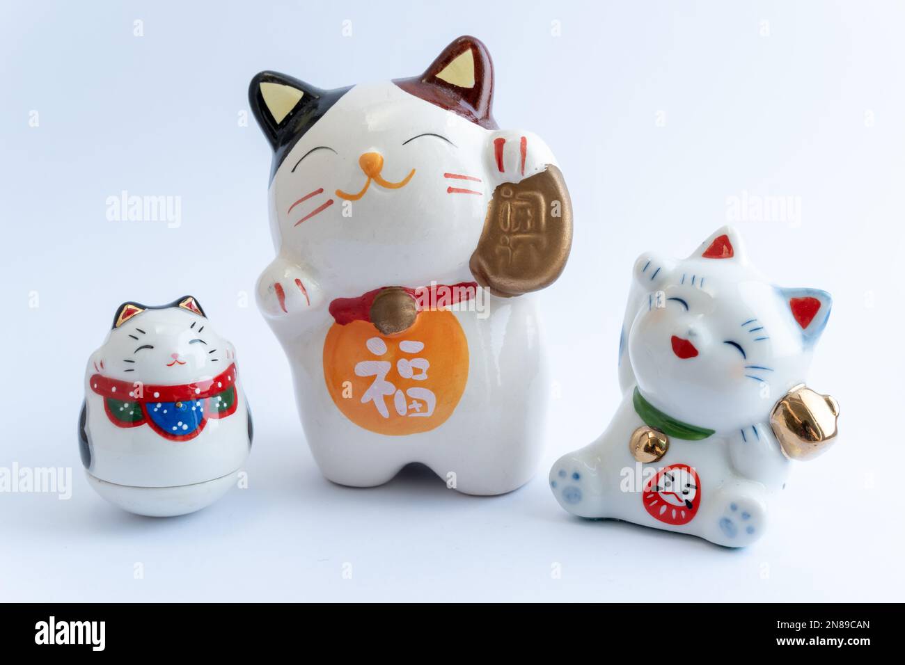 A Maneki-neko or also known as fortune cat in porcelain. Symbolizing luck and wealth, on a white isolated background. Stock Photo