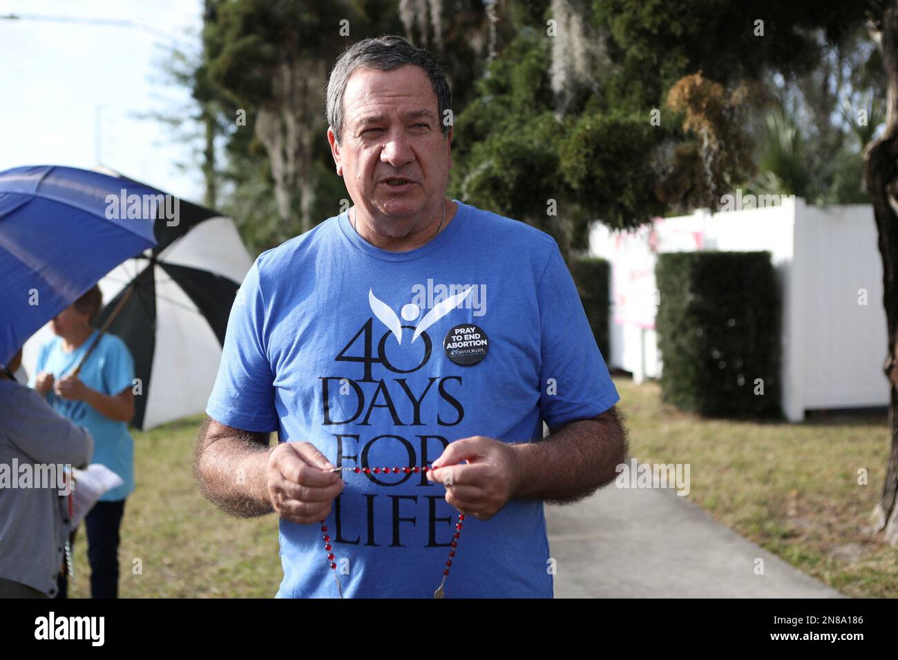 An unidentified anti-abortion rights activist representing his Catholic belief prays with other parishioners and protesters while they shout at patients arriving outside of the Bread and Roses Woman's Health Center, a clinic that provides abortions in Clearwater, Florida, February 11, 2023.  REUTERS/Octavio Jones Stock Photo