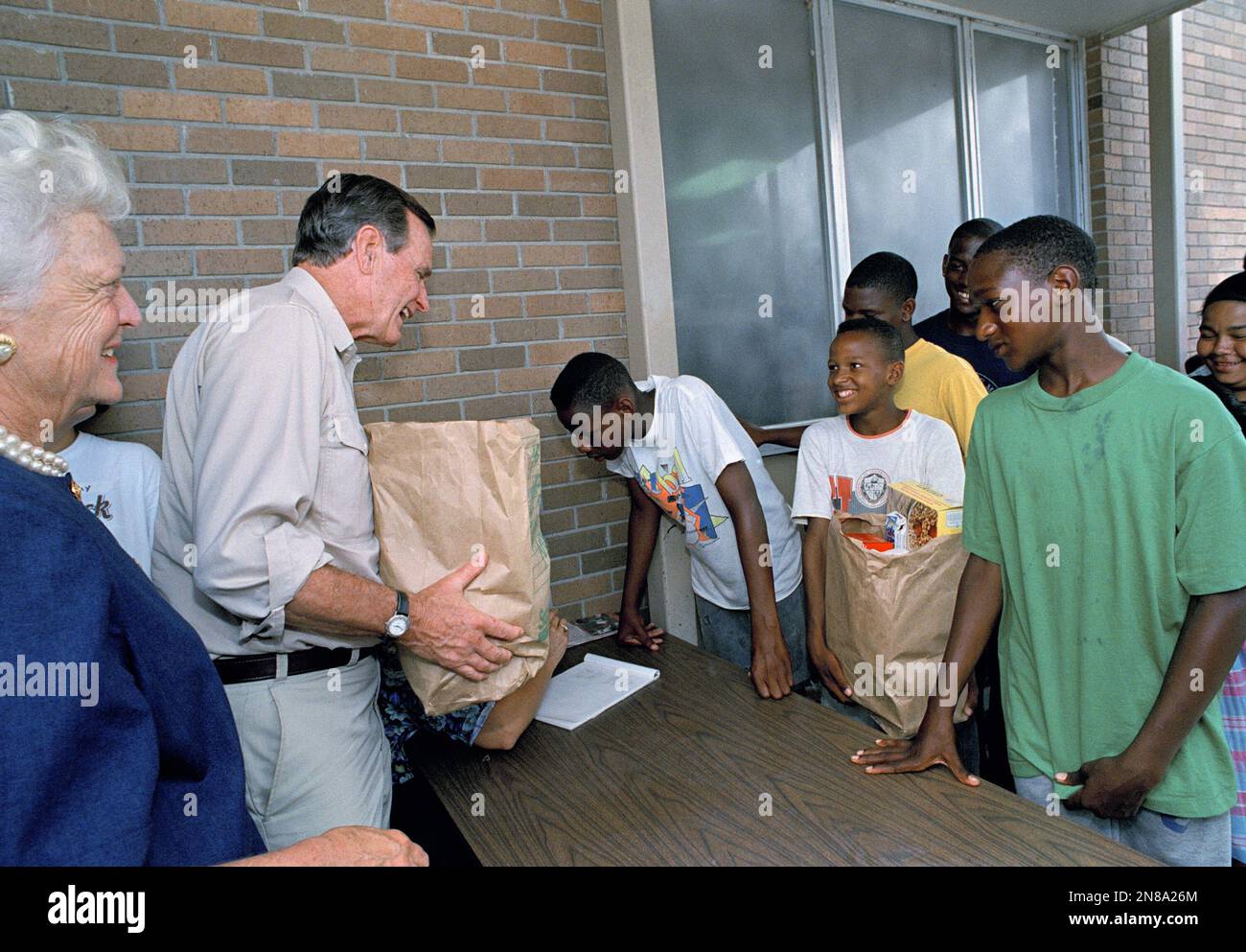 President H.W. Bush, and first lady Barbara Bush, far left, help