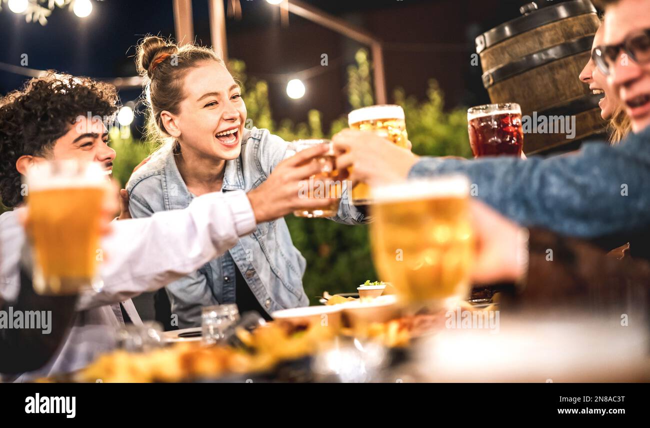 Happy friends clinking and toasting beer at brewery restaurant patio - Life style and beverage concept with young people having fun together out side Stock Photo