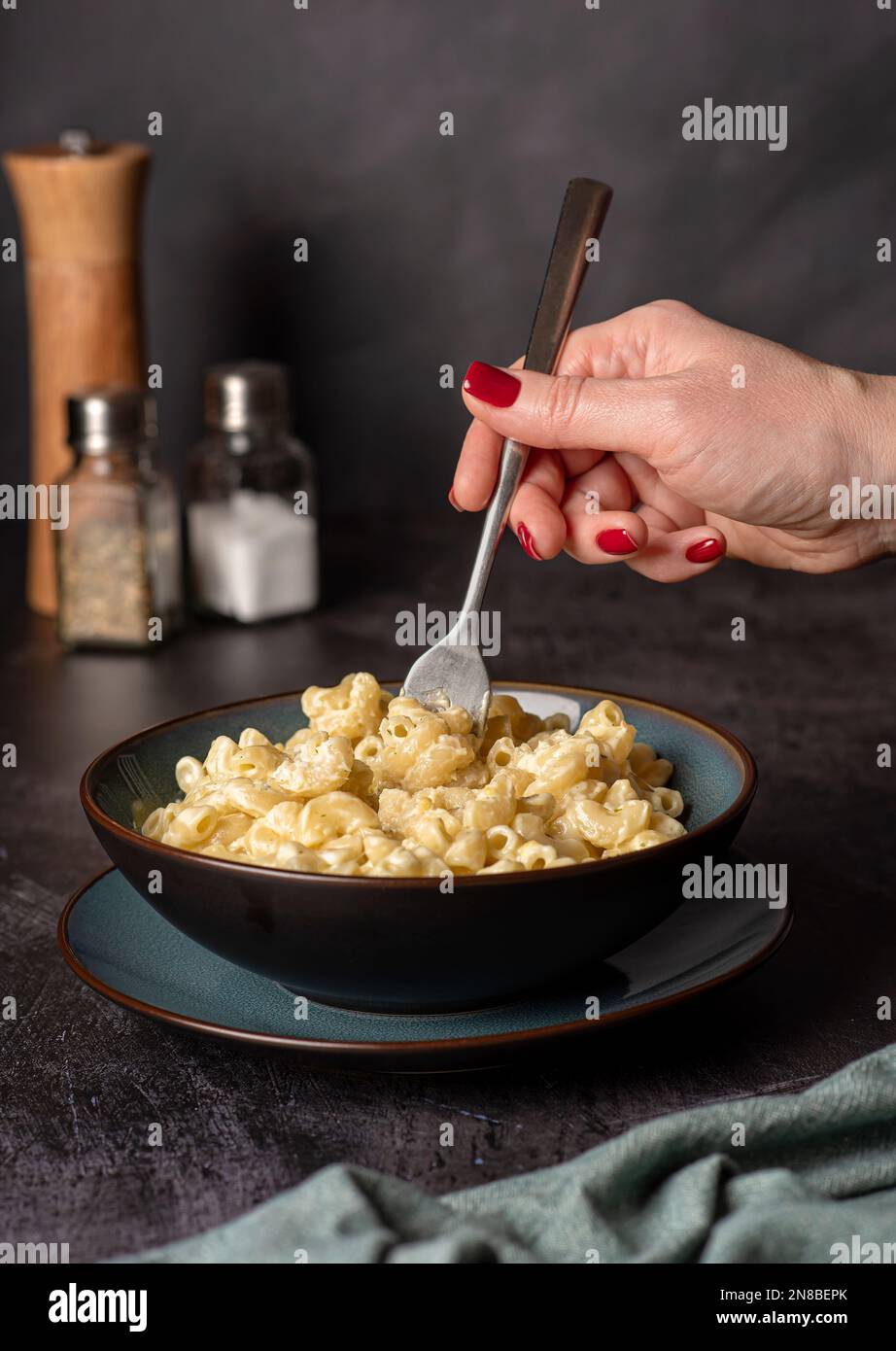 Food photography of pasta, macaroni with cheese, hand, noodles, creamy, fork, eating Stock Photo