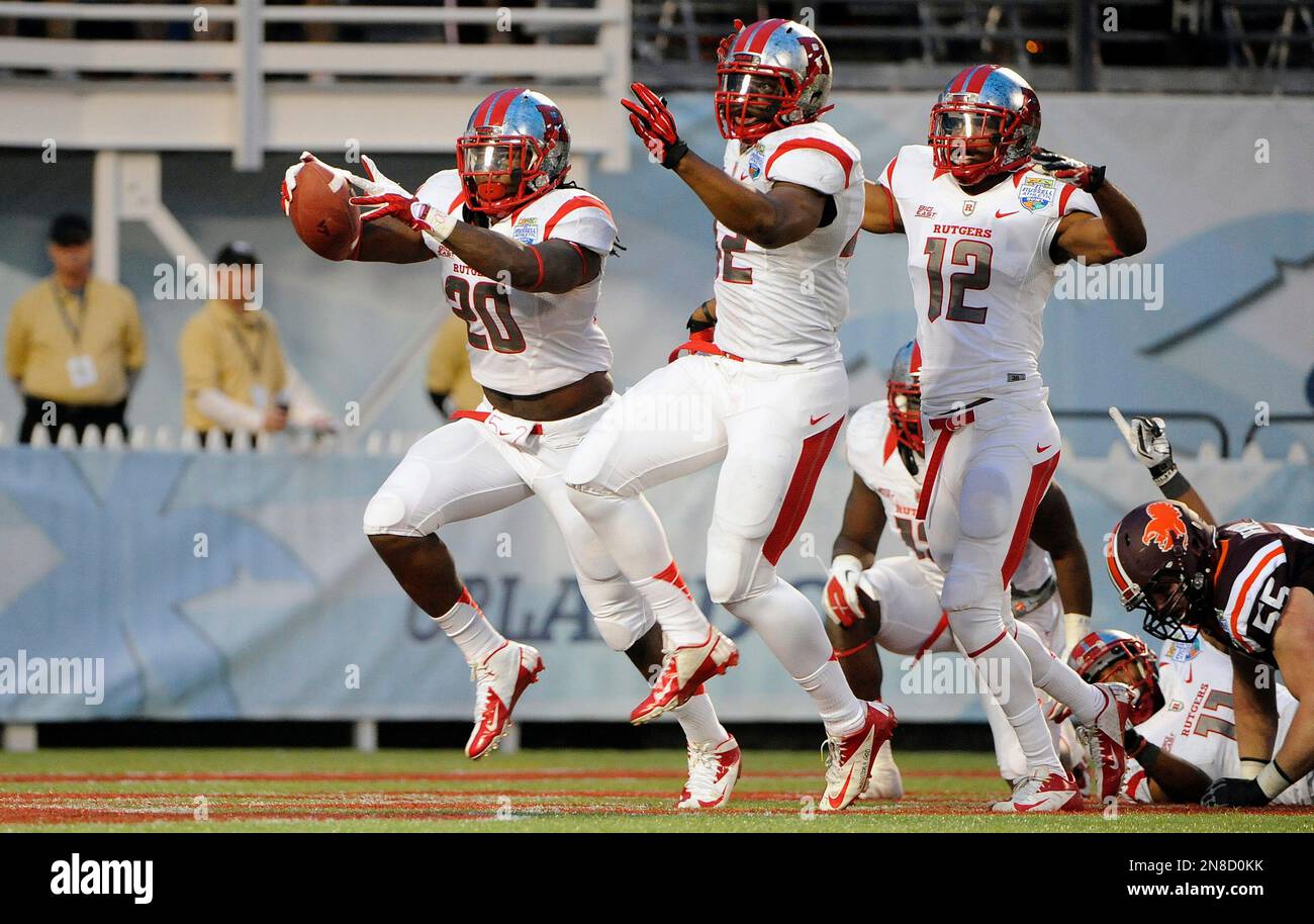 Rutgers linebacker Khaseem Greene, left, celebrates with linebacker Steve Beauharnais, center, and defensive back Marcus Cooper (12) after recovering a fumble in the end zone for a touchdown during the first quarter of the NCAA college football Russell Athletic Bowl game against Virginia Tech, Friday, Dec. 28, 2012, in Orlando, Fla. (AP Photo/Brian Blanco) Stock Photo