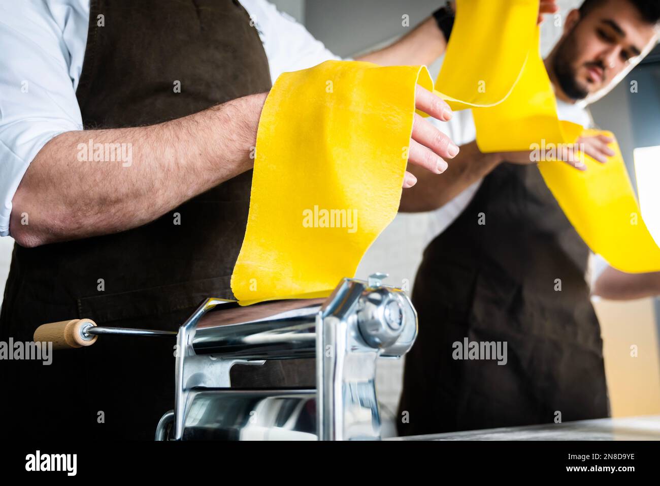 https://c8.alamy.com/comp/2N8D9YE/fresh-pasta-and-pasta-machine-italian-traditional-tagliatelle-young-men-in-apron-holding-the-dough-for-pasta-at-kitchen-2N8D9YE.jpg