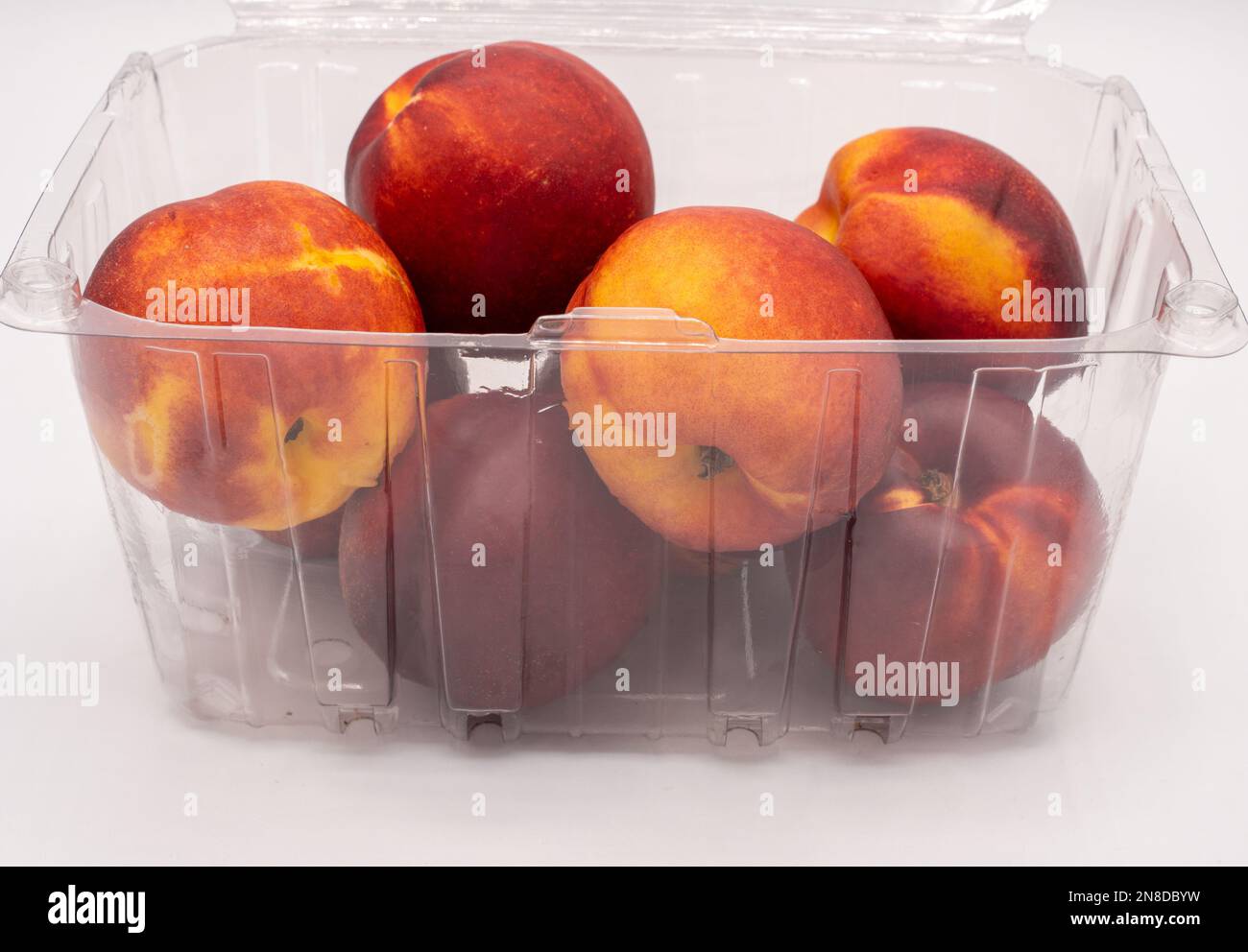 Nectarines in a plastic container on a white background. Stock Photo
