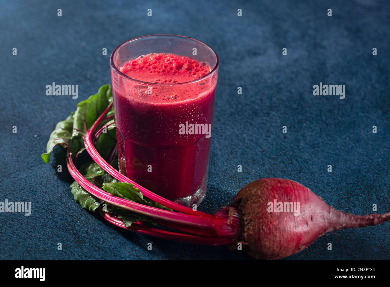 Organic beet juice in a glass on a dark blue surface with copy space Stock Photo