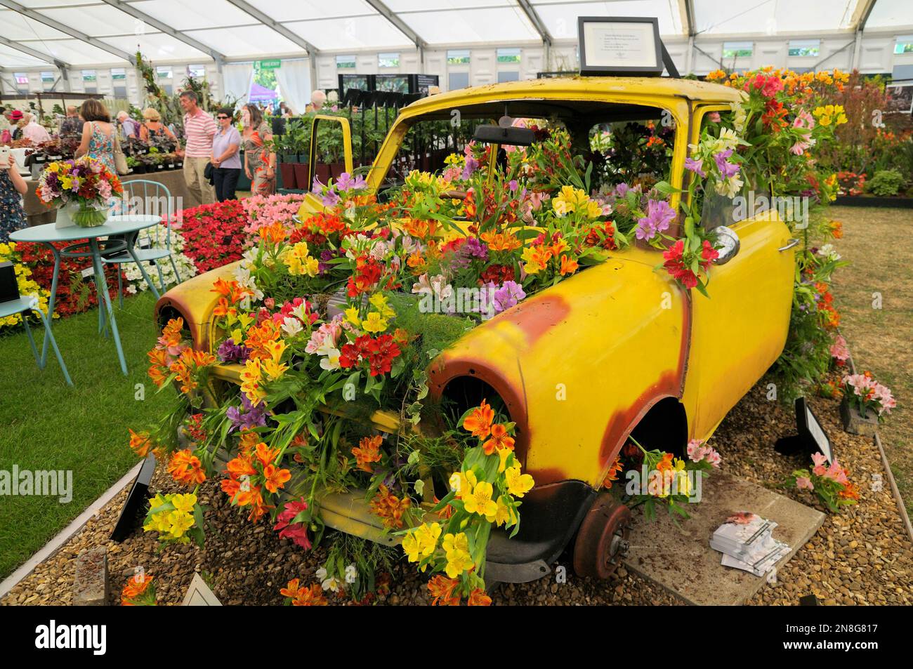 Eye-catching floral exhibit of Alstroemeria flowers in car body of rusted yellow mini, Floral Marquee, RHS Hampton Court Palace Garden Festival, UK Stock Photo