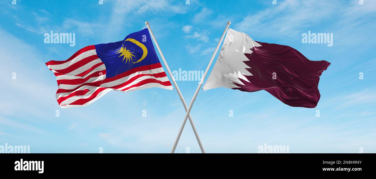 two crossed flags Qatar and Malaysia waving in wind at cloudy sky ...