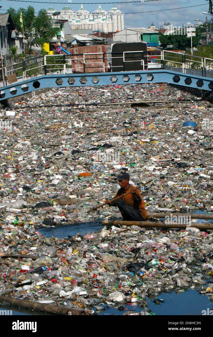 Recycling Raft A scavenger uses a raft as he collects plastic materials to be sold to ...