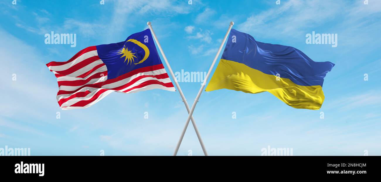 two crossed flags Ukraine and Malaysia waving in wind at cloudy sky ...