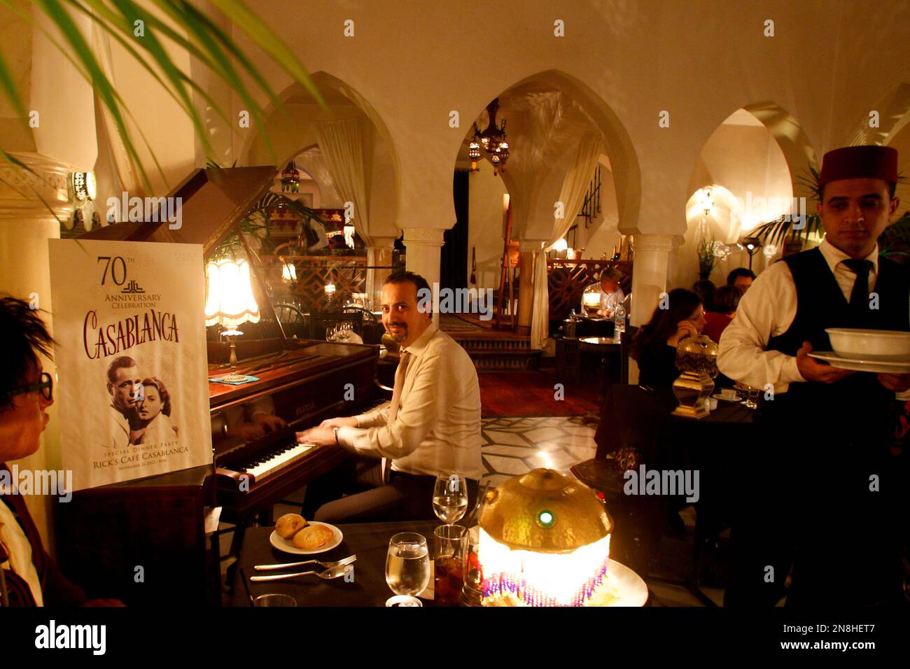 a-server-brings-a-plate-as-rick-s-cafe-pianist-issam-rear-center