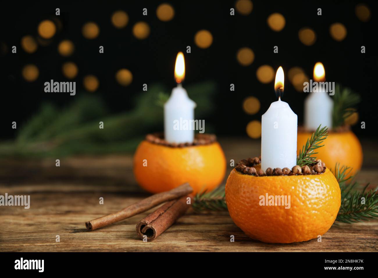 Burning candle in tangerine peel as holder on wooden table against ...