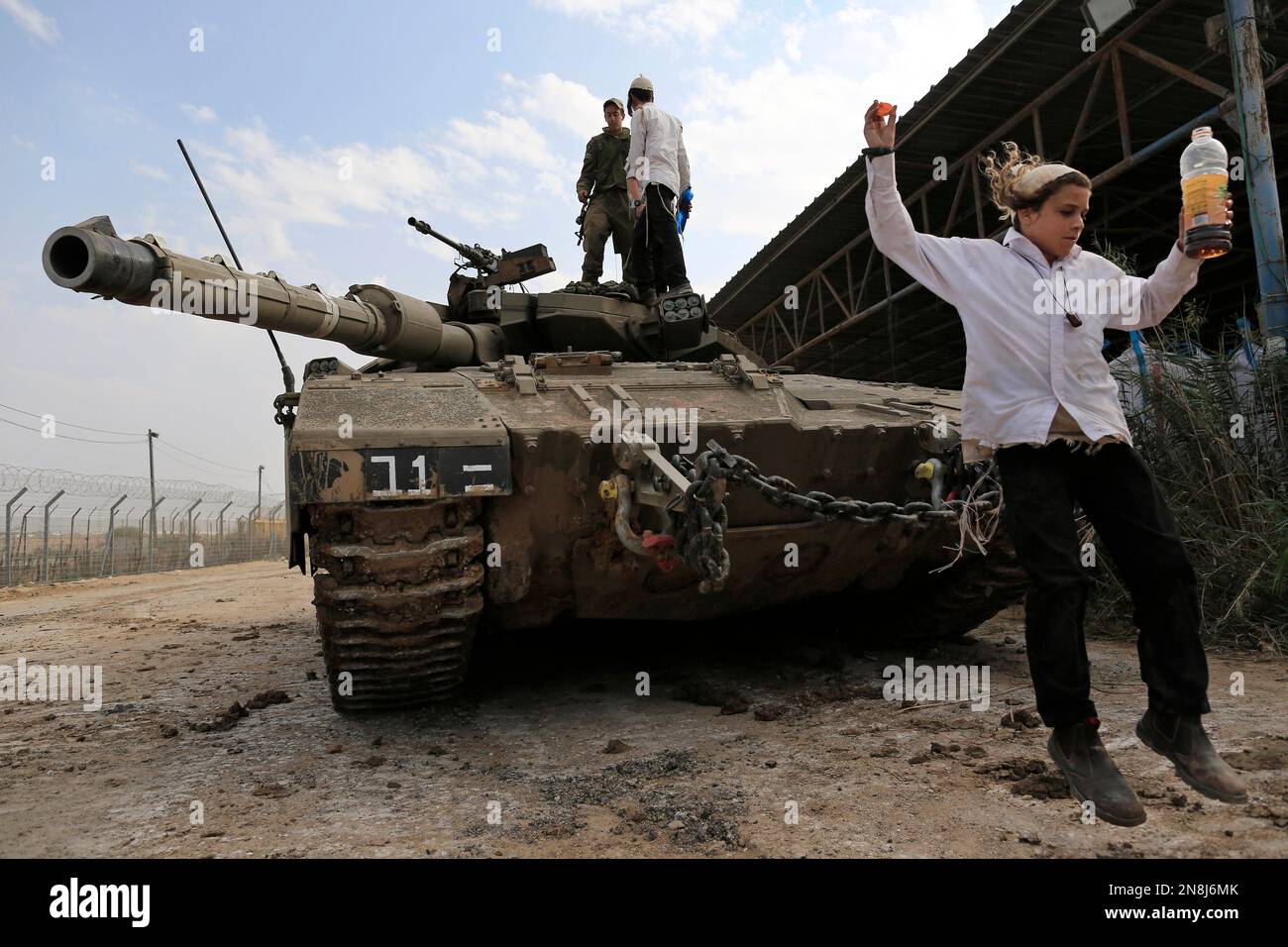 An ultra-Orthodox Jew of the Bratslav Hasidic sect, part of a team that gathered to show support for Israeli forces, jumps from a tank in southern Israel, close to the Israel Gaza Strip Border, Thursday, Nov. 22, 2012. A cease-fire agreement between Israel and the Gaza Strip's Hamas rulers took effect Wednesday night, bringing an end to eight days of the fiercest fighting in years and possibly signaling a new era of relations between the bitter enemies. (AP Photo/Tsafrir Abayov) Stock Photo