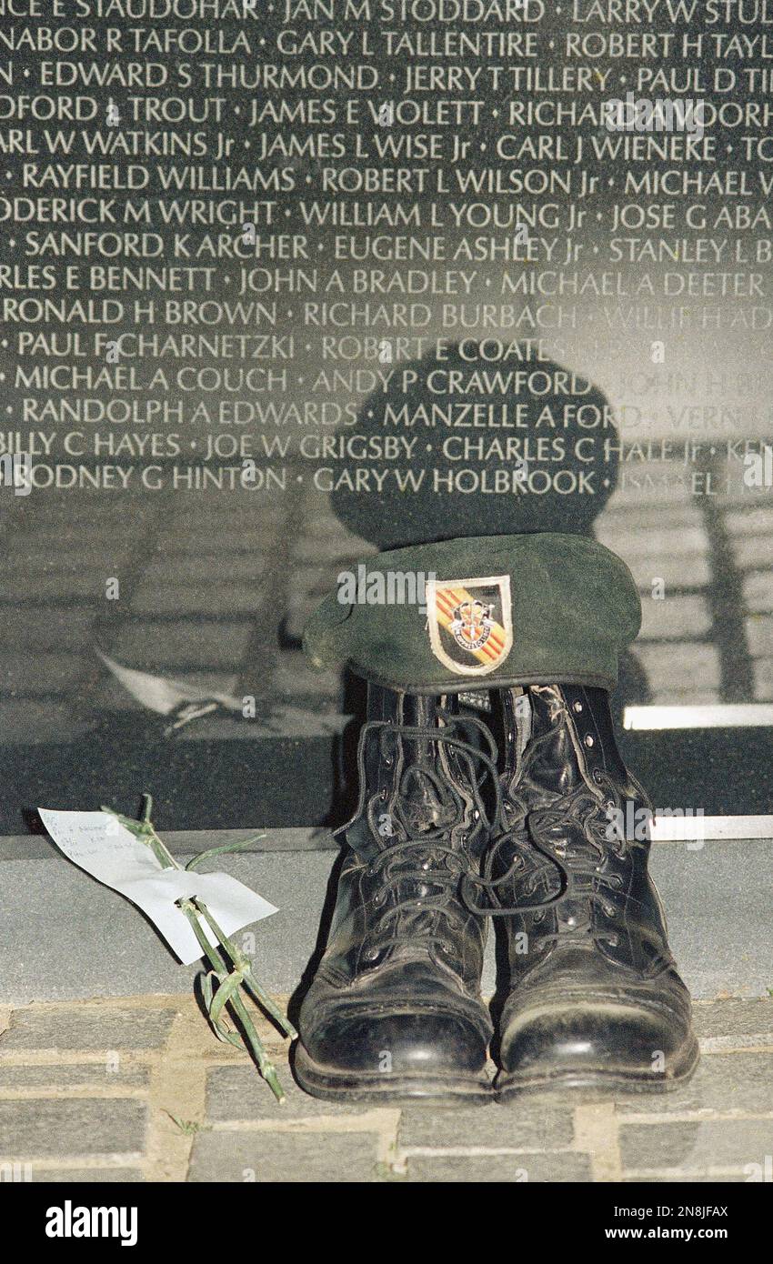 A pair of empty combat boots sits at the base of the black granite wall ...