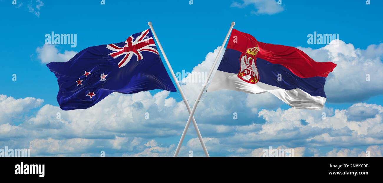 two crossed flags Serbia and New Zeeland waving in wind at cloudy sky ...