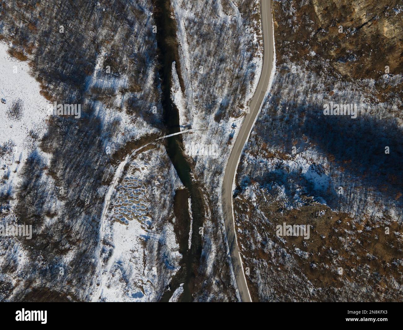 Aerial drone view on the road trough the hill and mountain in winter day covered with snow with rock and trees and river in Serbia Stock Photo