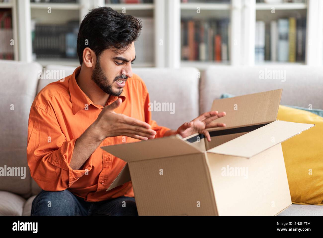Angry arab guy looking inside parcel box and gesturing Stock Photo