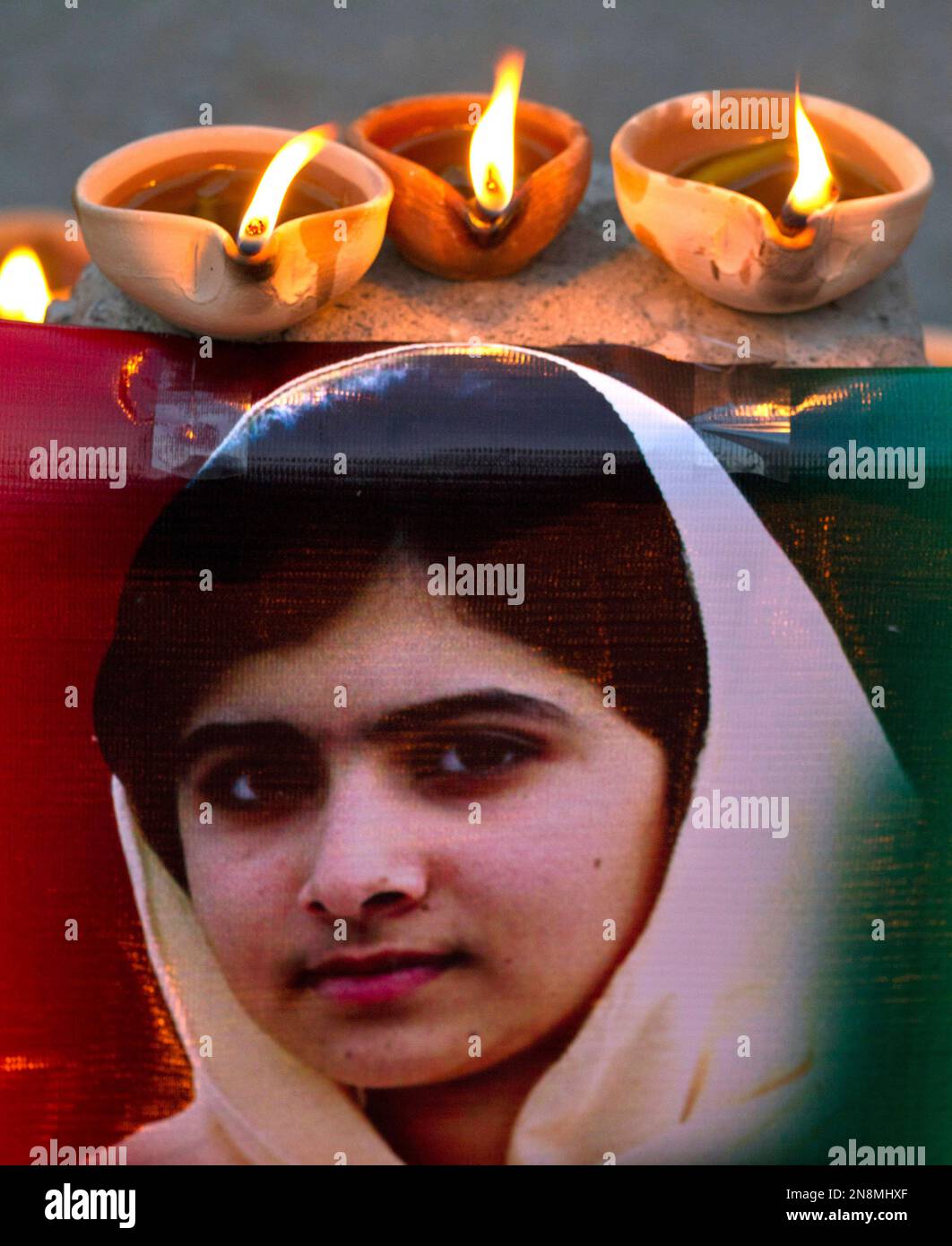 Clay Lamps Burn Near A Poster Of 15 year old Malala Yousufzai Placed By 
