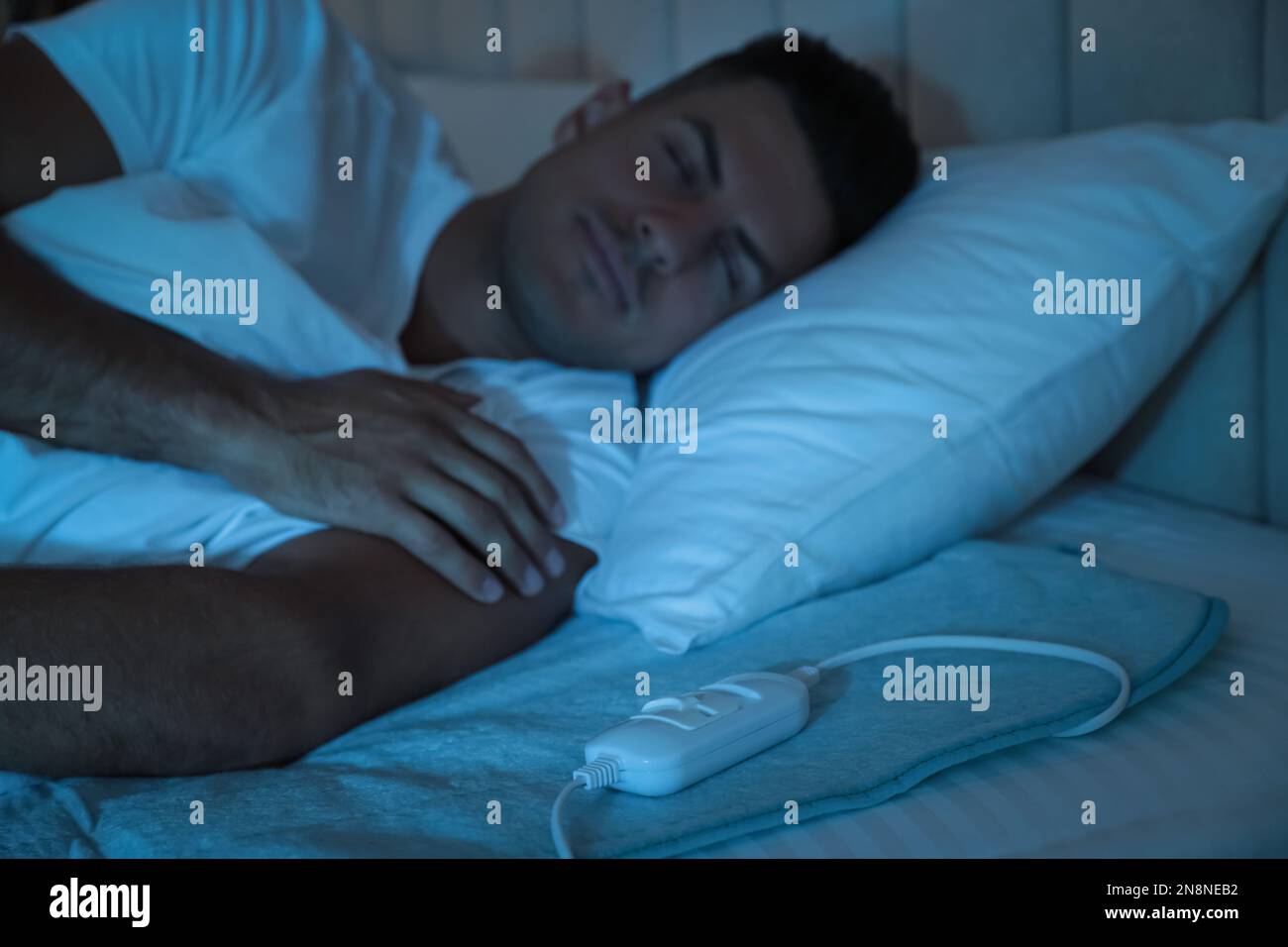 Man sleeping on electric heating pad in bed at night Stock Photo Alamy