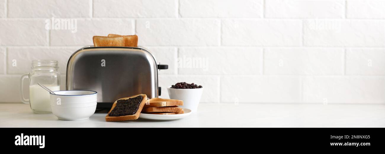 Modern toaster and delicious breakfast on table near brick wall, space for  text. Banner design Stock Photo - Alamy