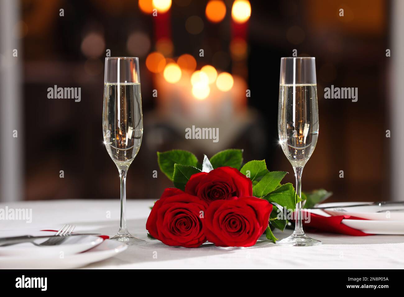 Romantic dinner table setting with glasses of champagne and red roses ...