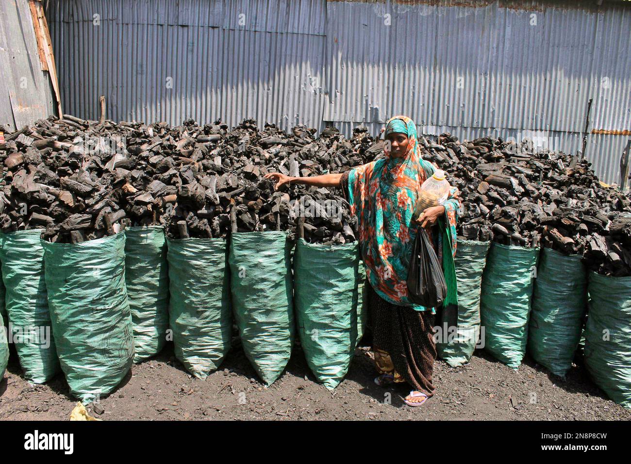 In this photo of Tuesday Oct. 30, 2012, A Somali charcoal trader scales charcoal at his charcoal shop in Mogadishu, Somali. Thousands of sacks of dark charcoal sit atop one another in Somalia's southern port city of Kismayo, an industry once worth some $25 million dollar a year to the al-Qaida-linked insurgents who controlled the region. The good news sitting in the idle pile of sacks is that al-Shabab militants can no longer fund their insurgency through the illegal export of the charcoal. Kenyan troops late last month invaded Kismayo and forced out the insurgents, putting a halt to the expor Stock Photo