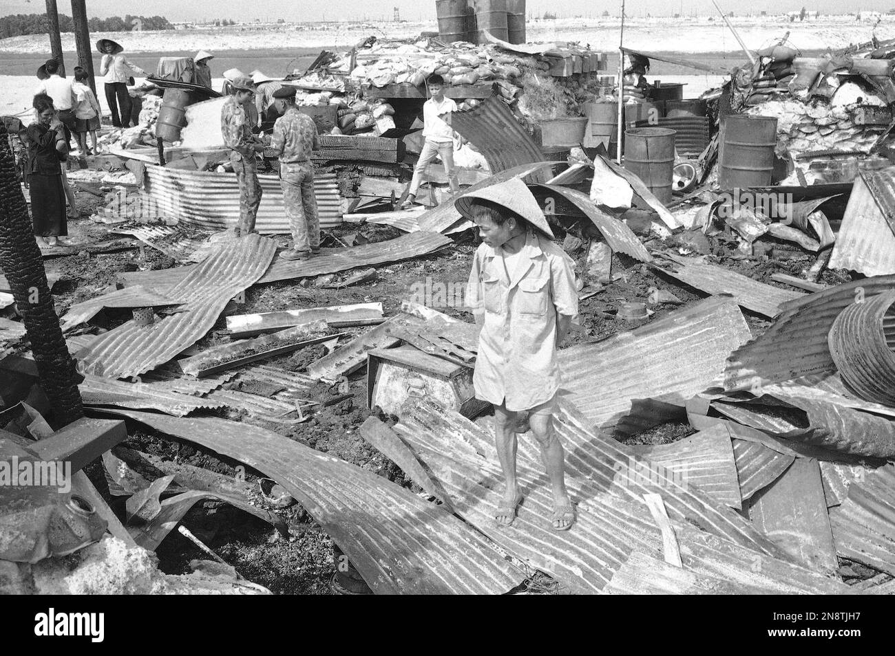 Hands clasped behind his back, a South Vietnamese man surveys debris of