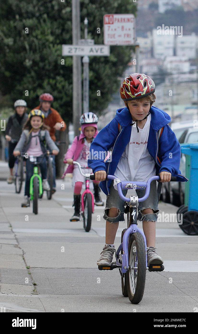 Henry Ades 6 rides his bicycle in front of his family as they