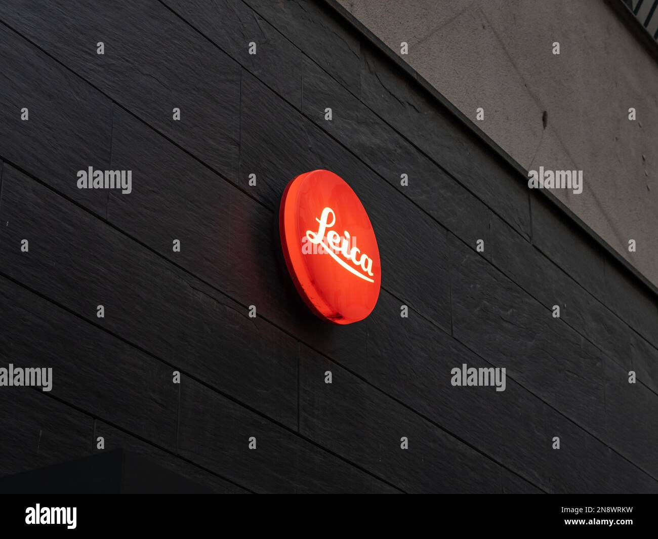 Leica store logo of the famous German camera and lens manufacturer. Illuminated brand sign in red color on the facade. High quality products. Stock Photo
