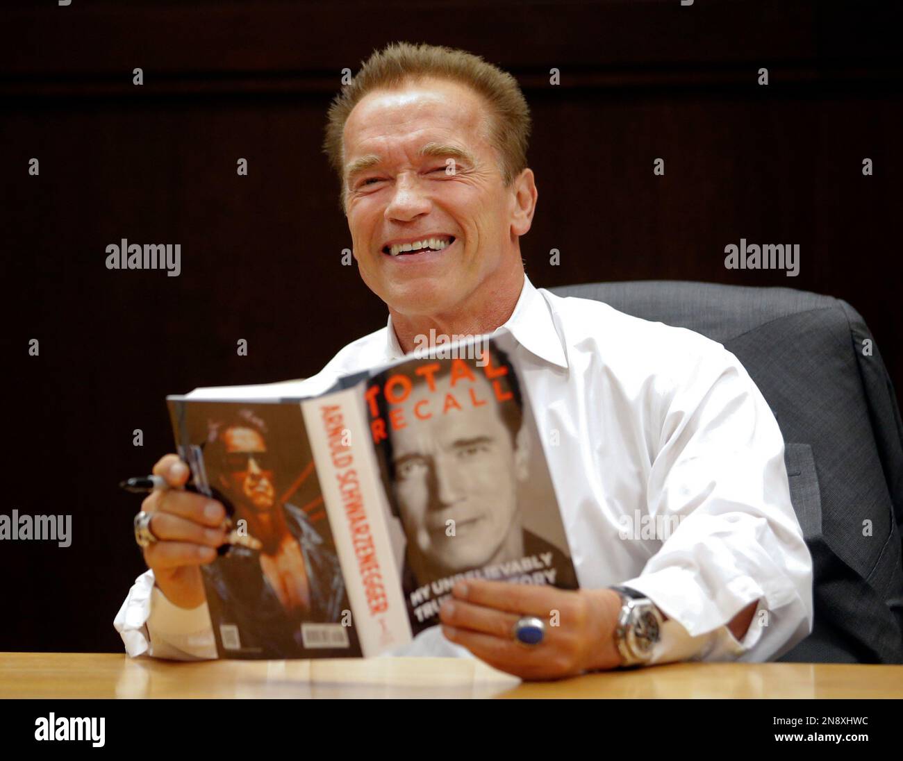 Former California Gov. Arnold Schwarzenegger holds his book "Total