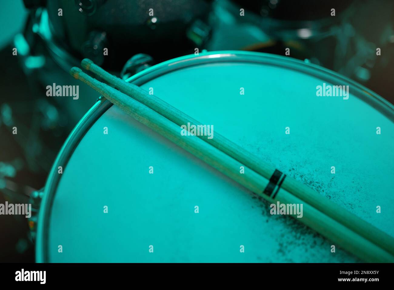 Top view of sticks on drums instrument in music studio, production or live band in neon green light. Background closeup of drum kit of musician Stock Photo
