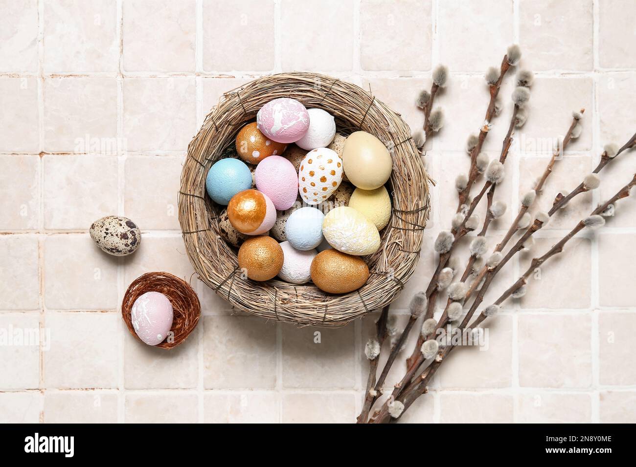 Nest with Easter eggs and willow branches on light tile Stock Photo - Alamy