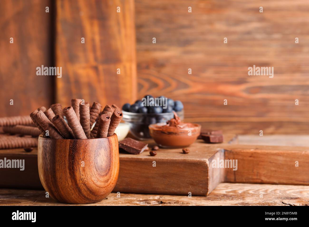 Bowl with delicious chocolate wafer rolls on brown wooden table Stock Photo