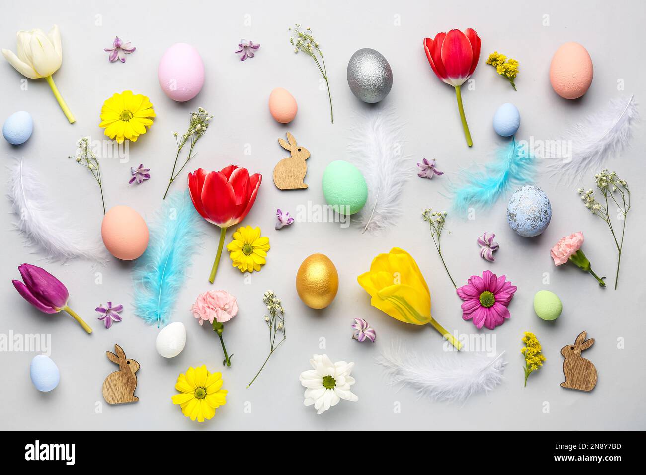 Composition with Easter eggs, feathers and different flowers on light background Stock Photo