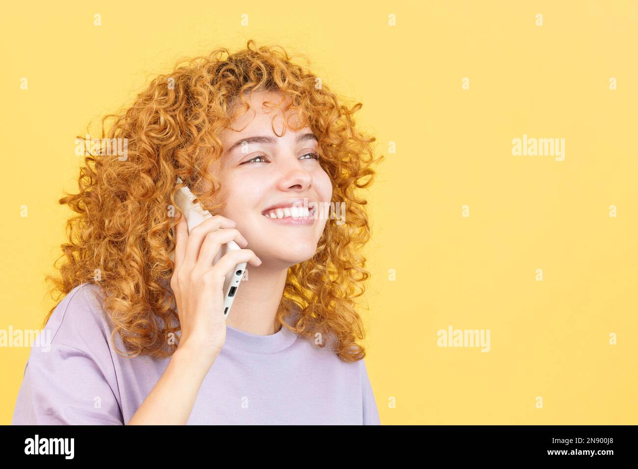 Happy woman with curly hair talking to the mobile Stock Photo